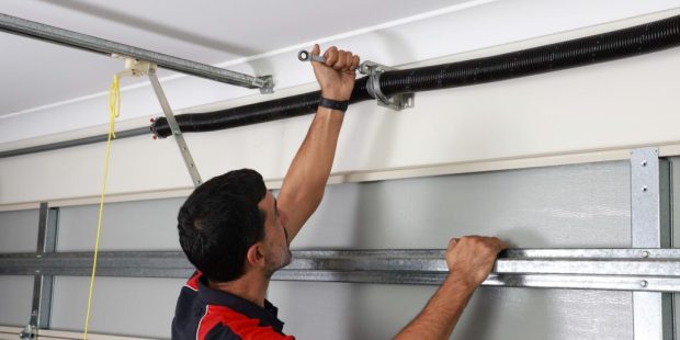 Homeowner inspecting garage door roller for cracks and wear damage during routine maintenance