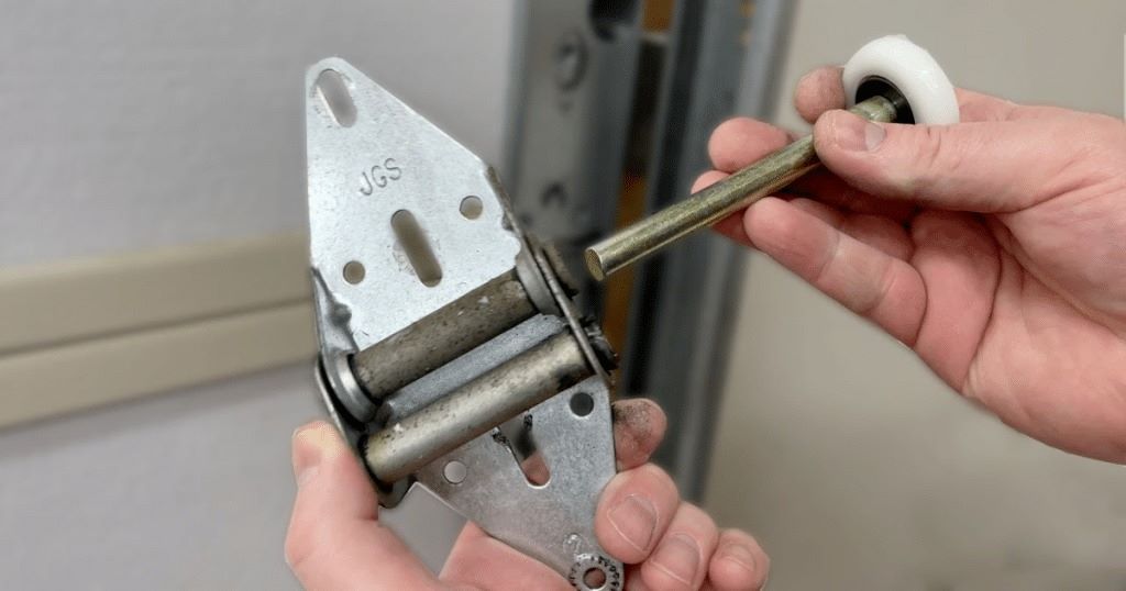 Professional garage door technician replacing worn steel roller with new nylon roller in residential garage