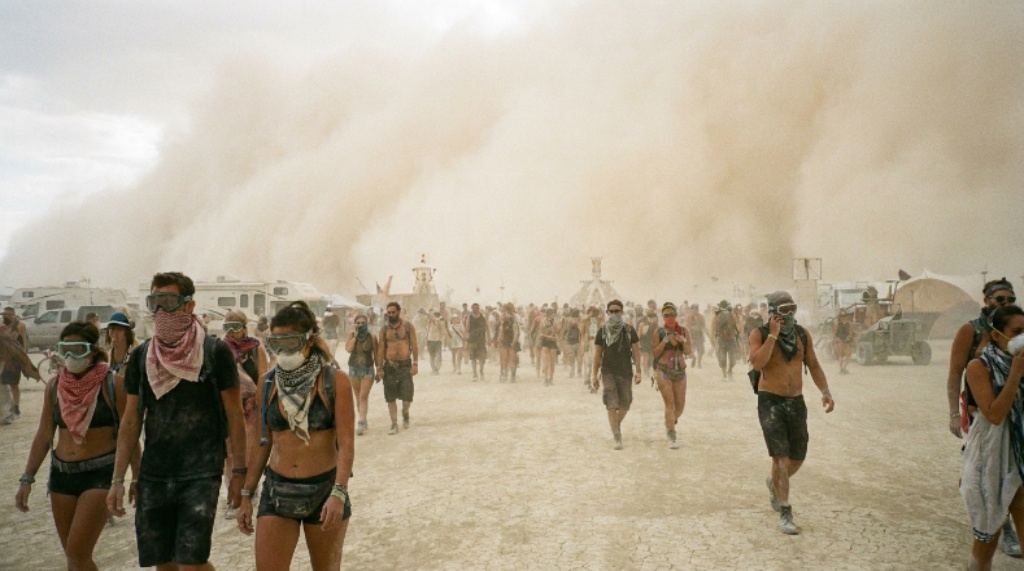 Dust storm whiteout rolling across the Black Rock Desert playa at Burning Man with participants in goggles and dust masks