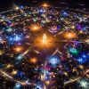 Aerial view of Black Rock City circular street grid in Nevada's Black Rock Desert at night with art installations lit up during Burning Man 2026