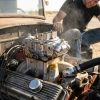 Classic hot rod engine showing carburetor inspection process