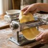Stainless steel Marcato pasta machine with fresh noodles on a sunny Florida kitchen counter.