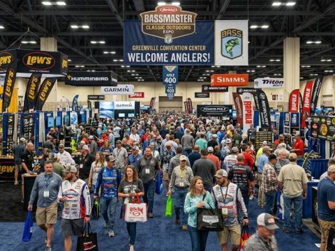 Crowds walking through the Bassmaster Classic Outdoors Expo floor surrounded by fishing gear exhibitor booths at Greenville Convention Center 2027