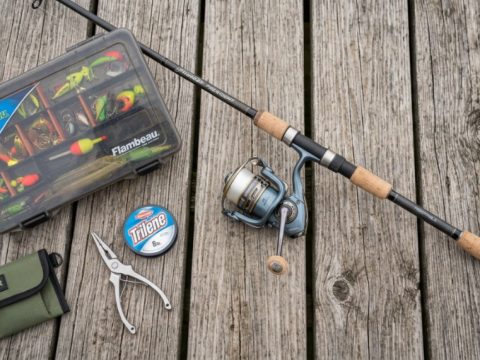 A beginner spinning rod and reel laid out on a wooden dock.