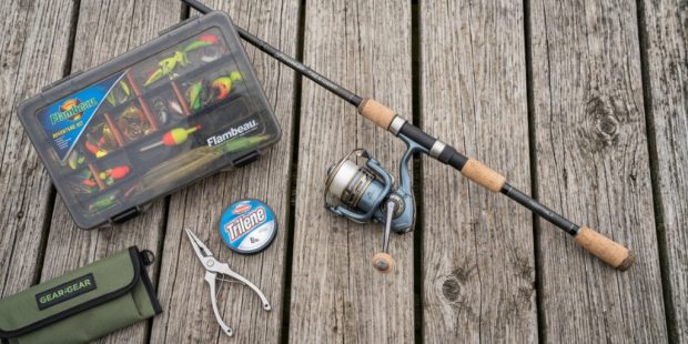 A beginner spinning rod and reel laid out on a wooden dock.